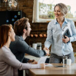 Happy financial advisor greeting young couple at their home.