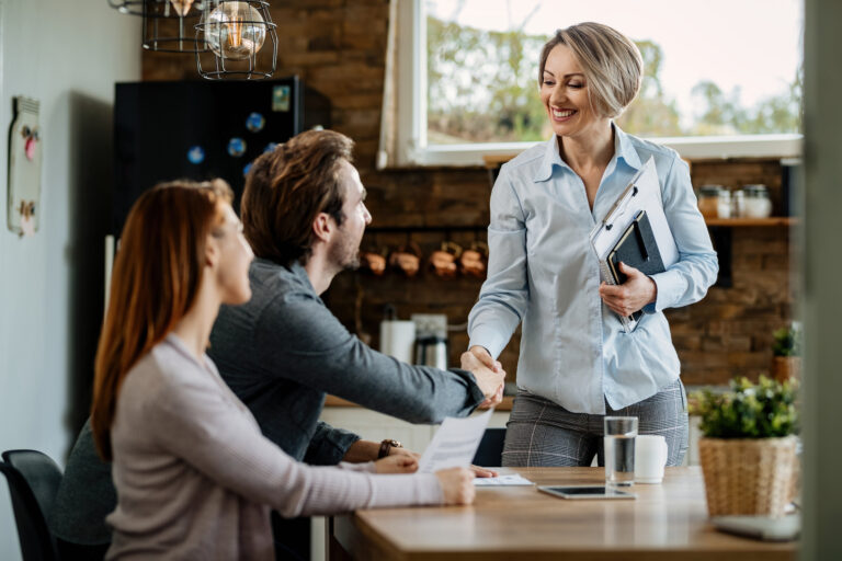 Happy financial advisor greeting young couple at their home.