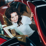 selective focus of smiling pretty woman sitting in new red car