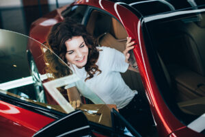 selective focus of smiling pretty woman sitting in new red car